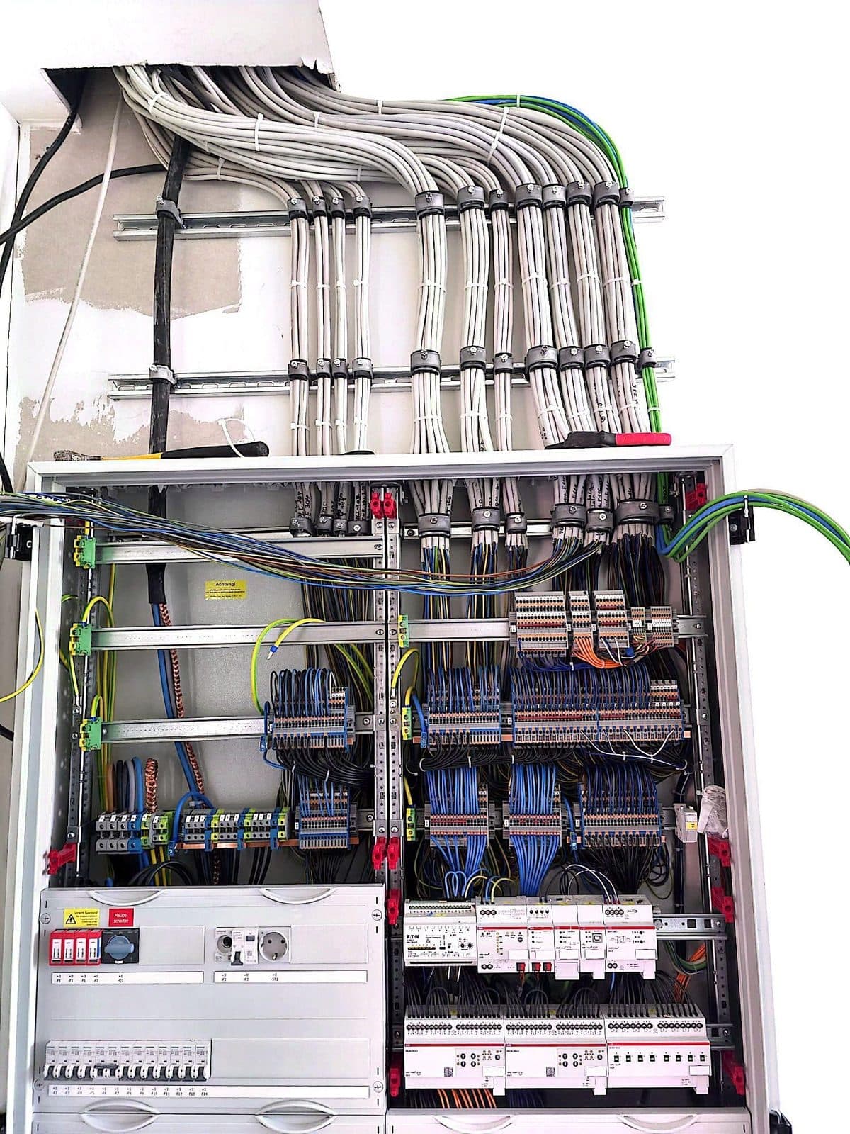 Gebündelte Leitungen über einem geöffneten Schaltschrank und ihre Einführung zu den Klemmenreihen